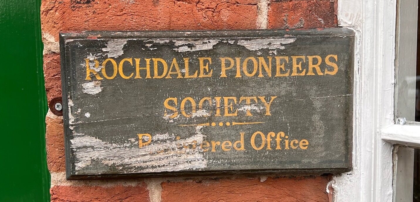 An aged door sign that says “Rochdale Pioneers Society – Registered Office”