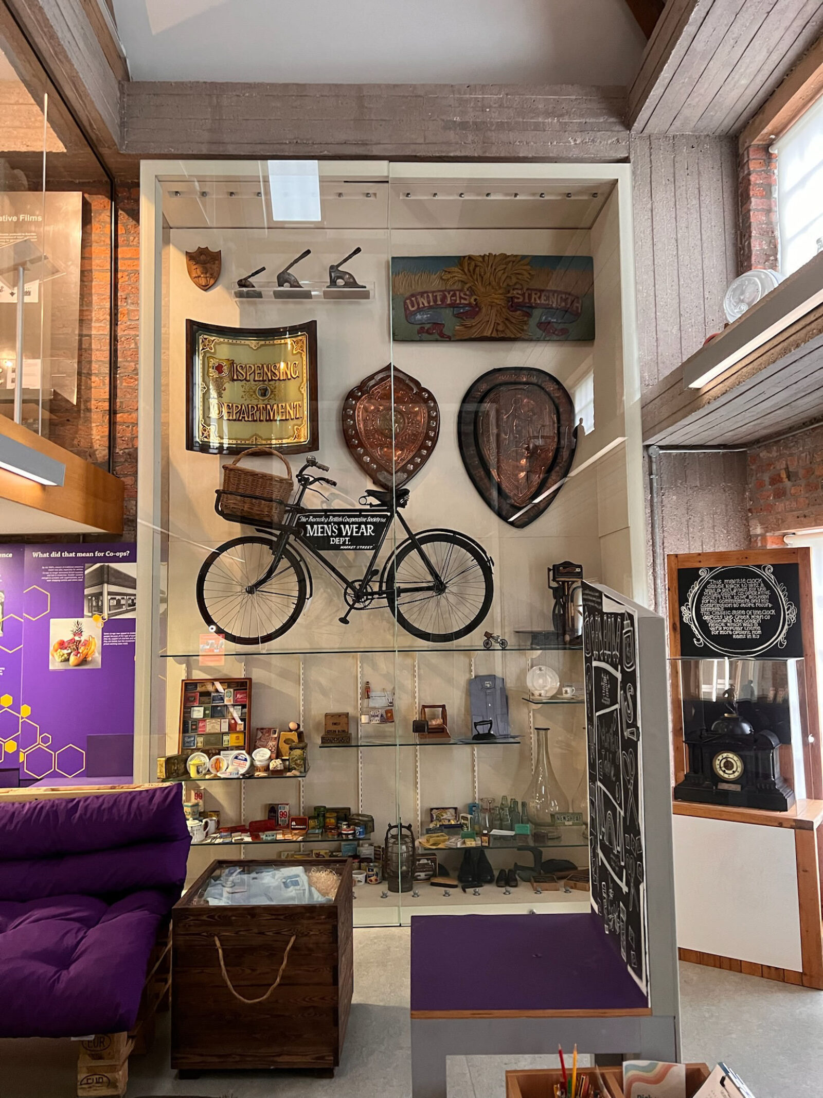 A photo of a large display of objects in the Pioneers Museum in Rochdale, showcasing emblems, a bicycle and several household products
