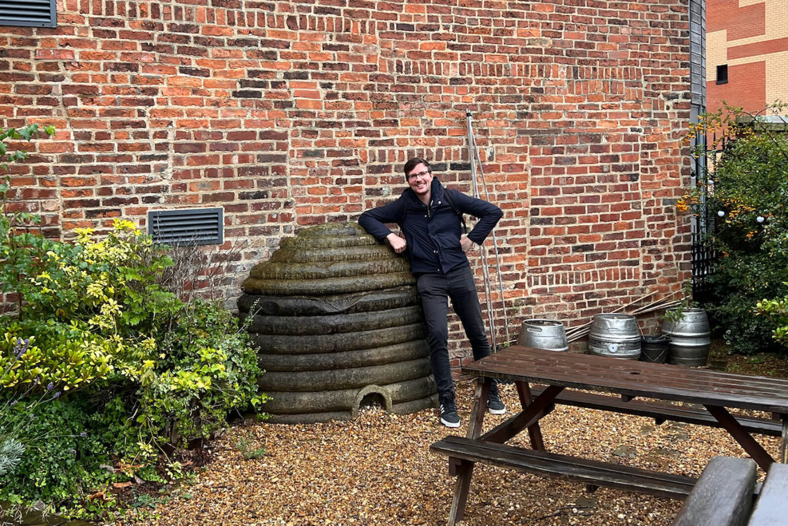 A smiling dude posing next to a giant beehive ornament made out of stone