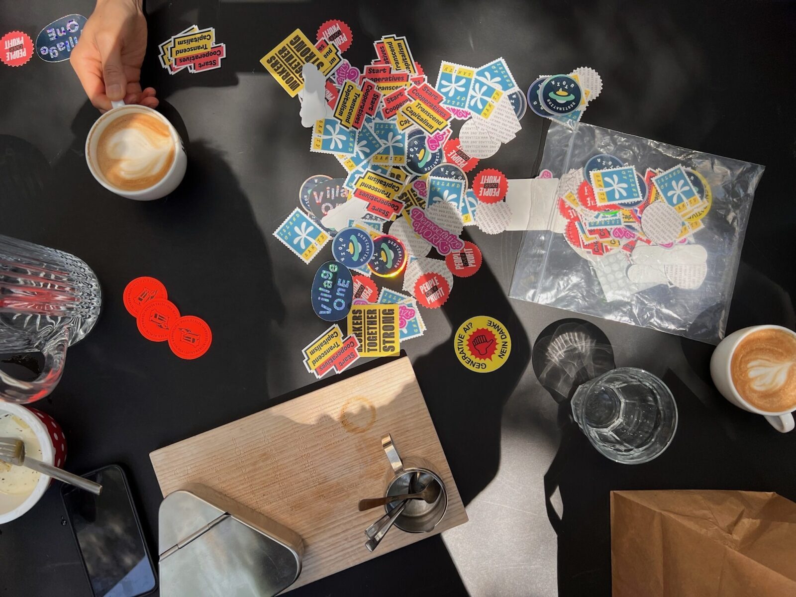 Top-down photo of a desk, with coffee cups, glasses and lots of colorful stickers