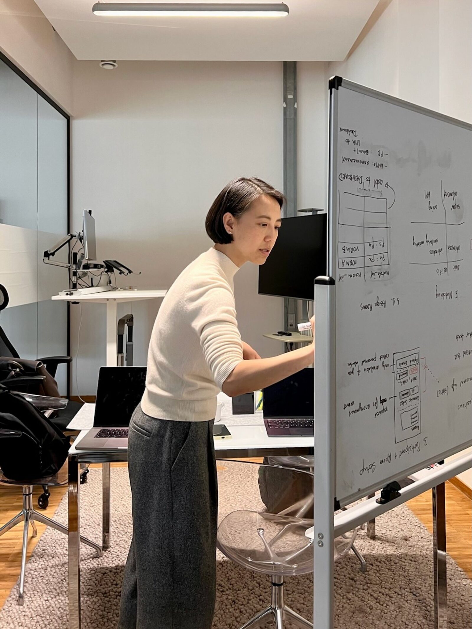 A developer standing at a whiteboard in a meeting room, sketching out software architecture