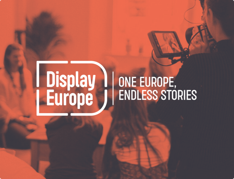 The logo of Display Europe in white set against a duotone image depicting a group of people being filmed.