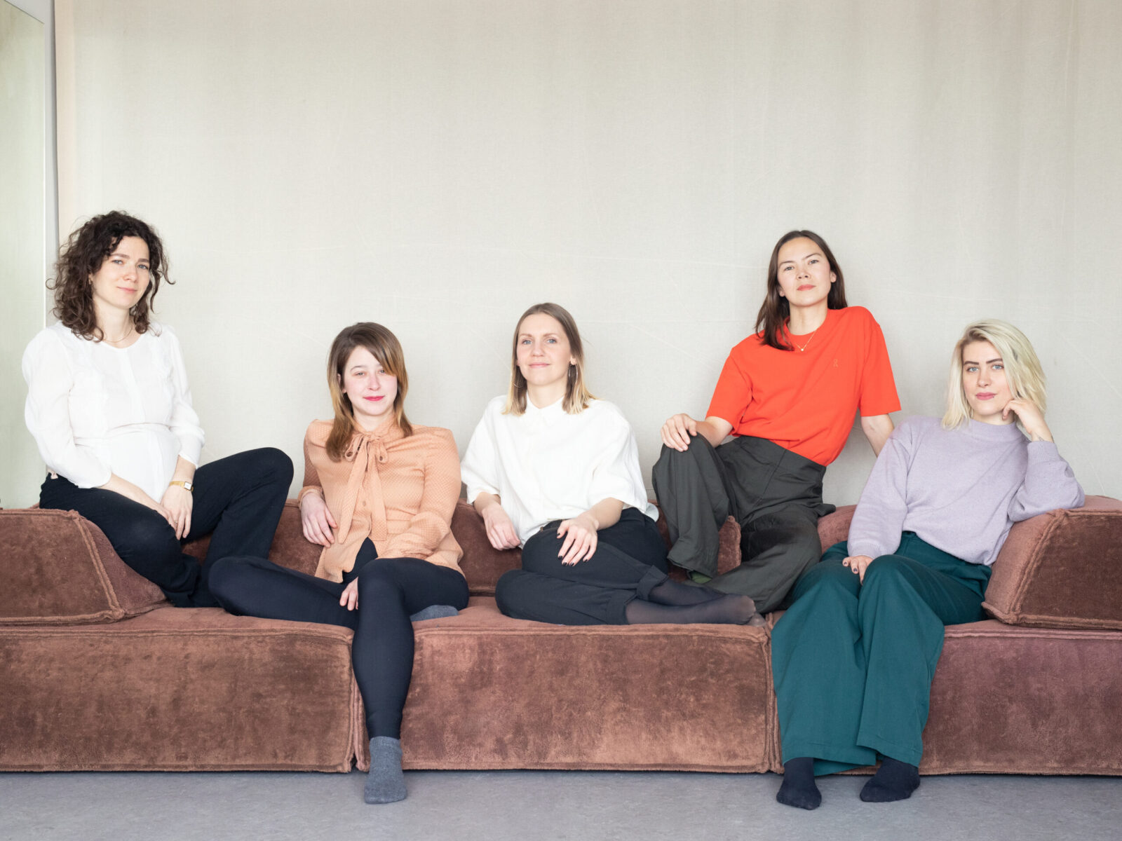 The five female founders of zoraLit hanging out on a large couch, group photo, everyone looking confidently at the camera